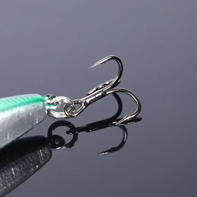Close-up of a sharp silver fishing hook attached to a vibrant floating pencil lure, ideal for topwater fishing.