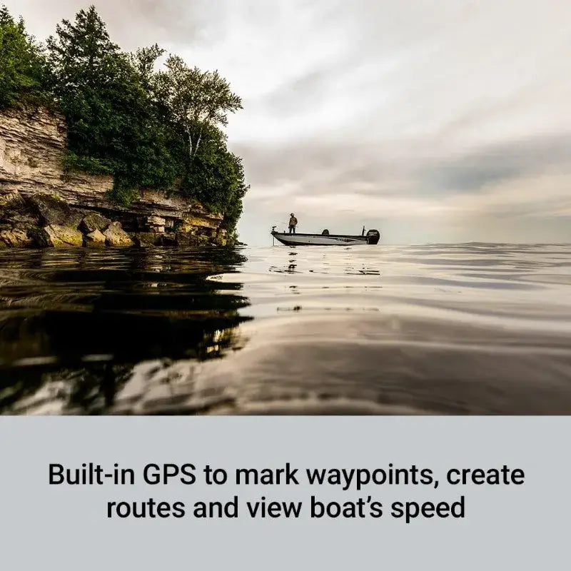 Person fishing from a boat on a lake with a scenic shoreline, utilizing GPS for navigation.