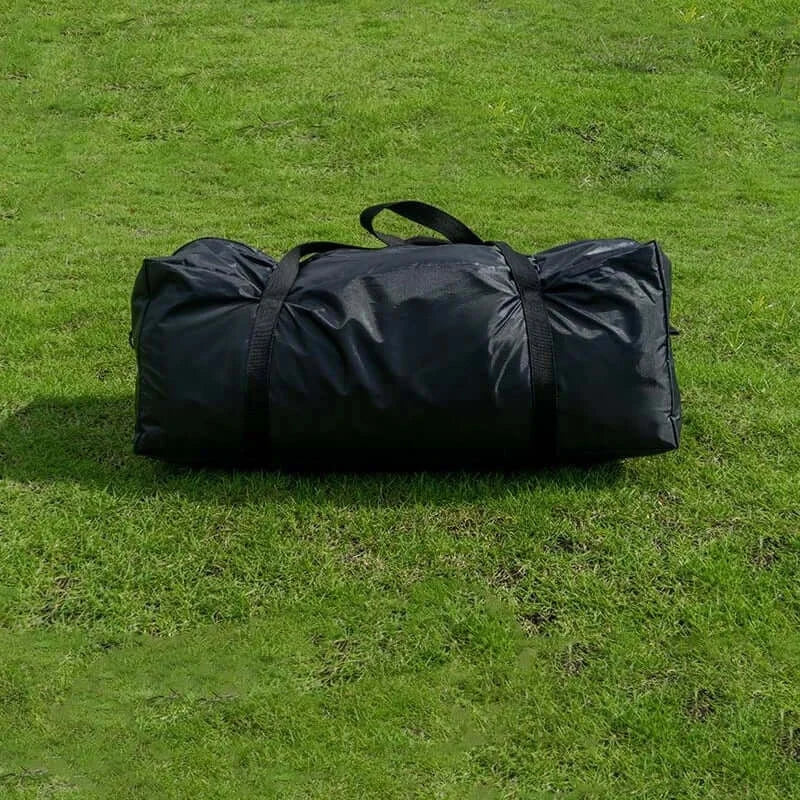 Black camping gear storage bag on green grass, designed for portable outdoor use.