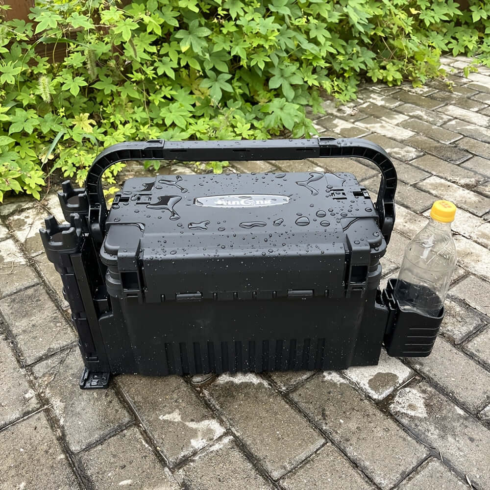 YUNCONG double-layer fishing tackle box set in black, waterproof ABS material, resting on stone pavement with water droplets.